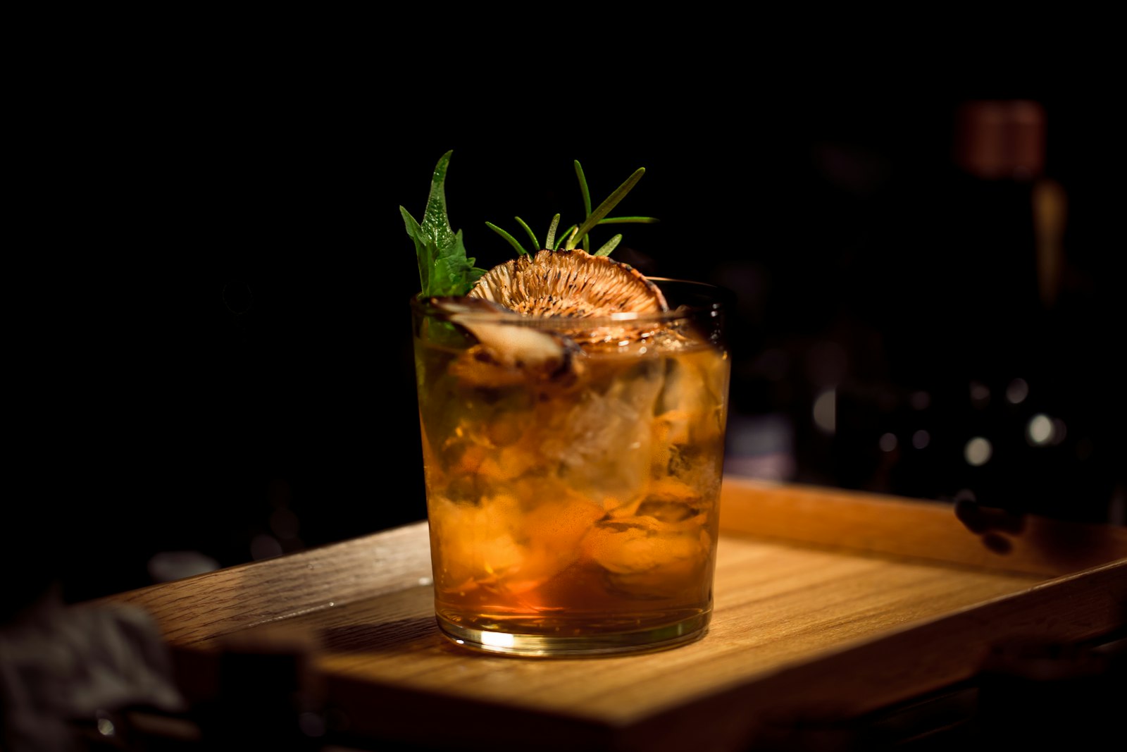 Ein bernsteinfarbener Cocktail auf einem Holztablett